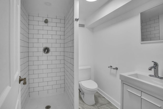 bathroom featuring vanity, a shower stall, toilet, and baseboards