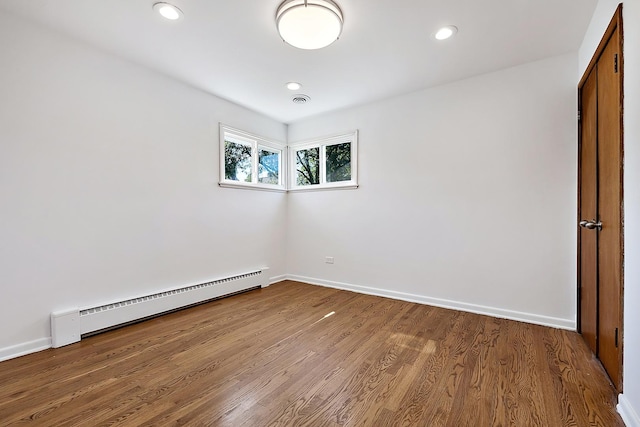 unfurnished room with baseboards, baseboard heating, wood finished floors, and recessed lighting