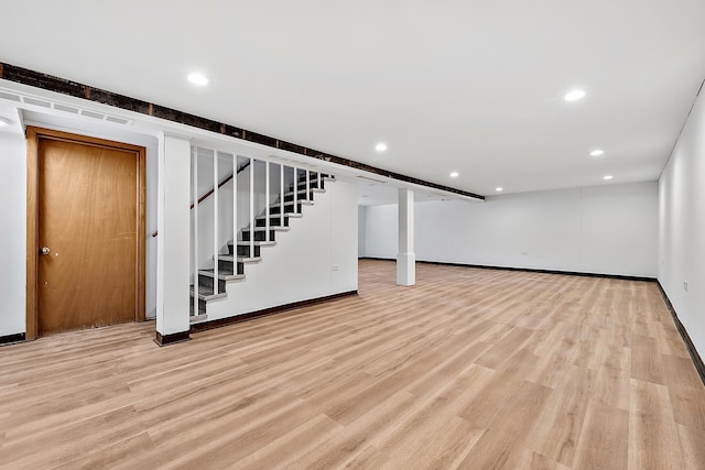 finished basement with light wood-style flooring, stairs, and recessed lighting