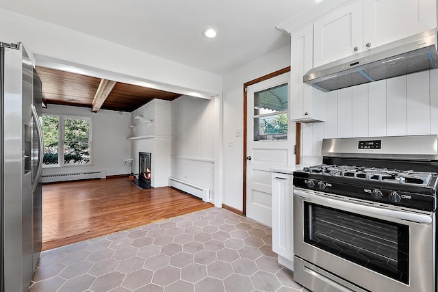 kitchen featuring stainless steel appliances, a large fireplace, under cabinet range hood, and baseboard heating