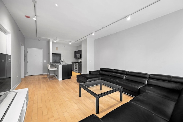 living room with light wood-style floors and track lighting