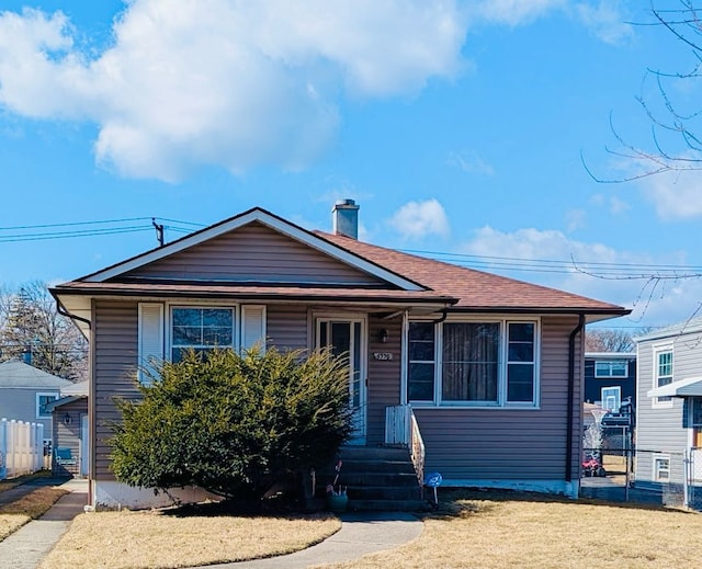 view of front of property with a front lawn, a chimney, and fence