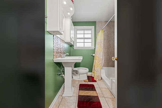 full bathroom with tile patterned floors, baseboards, toilet, and shower / bath combo with shower curtain