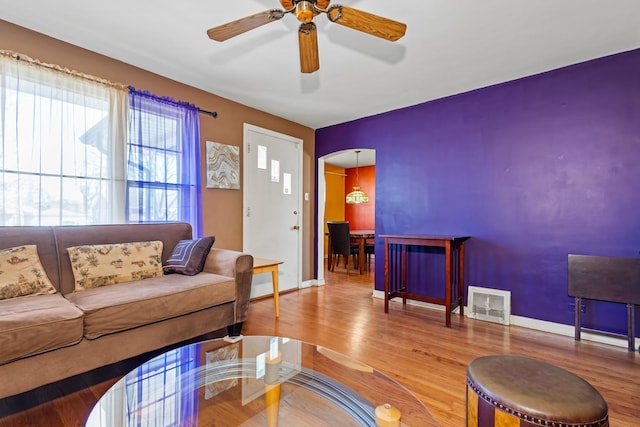 living area featuring arched walkways, wood finished floors, visible vents, and baseboards