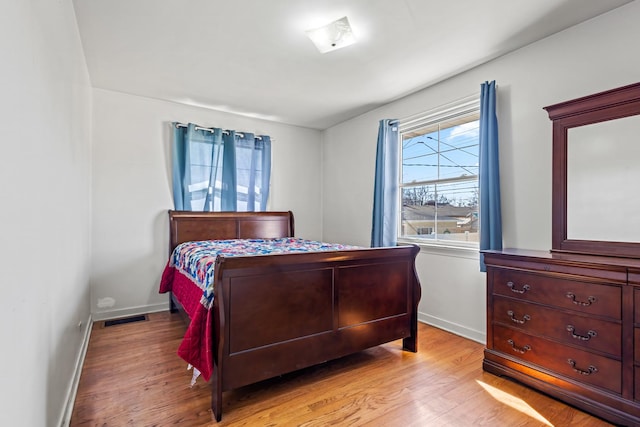 bedroom featuring light wood finished floors, visible vents, and baseboards