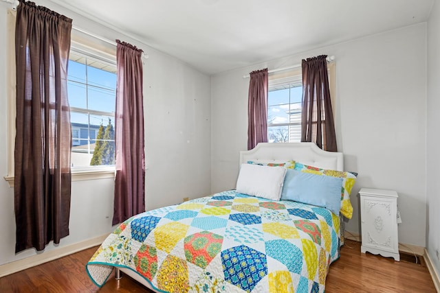 bedroom featuring visible vents, baseboards, and wood finished floors