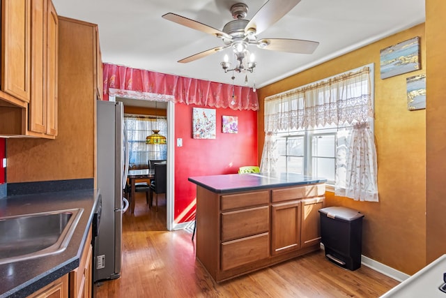 kitchen with dark countertops, brown cabinets, light wood-type flooring, and freestanding refrigerator