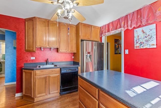 kitchen featuring wood finished floors, stainless steel fridge with ice dispenser, a sink, dishwasher, and dark countertops