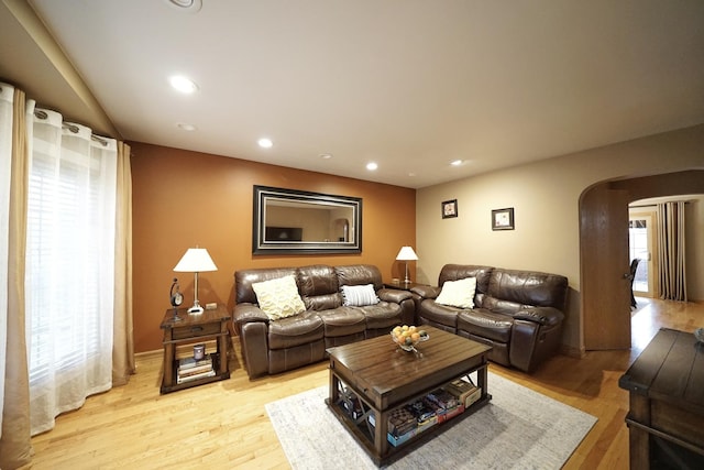 living area with arched walkways, light wood-type flooring, and recessed lighting