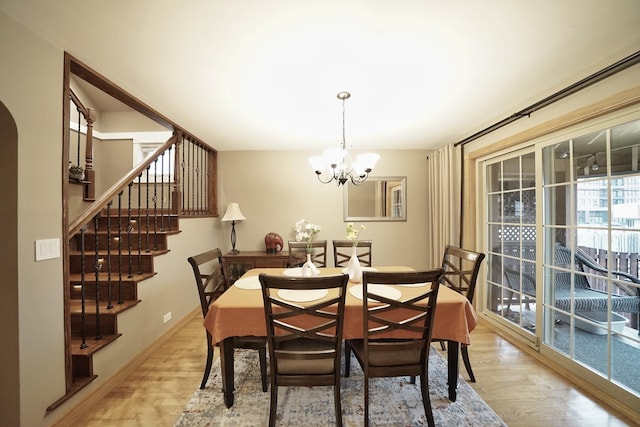 dining area featuring baseboards, stairs, light wood-style flooring, and a notable chandelier