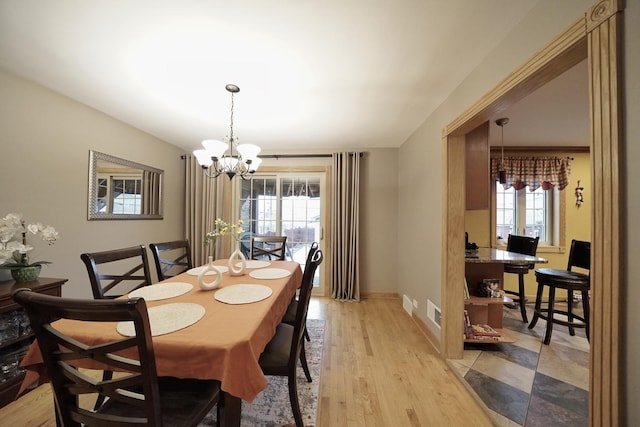 dining room with visible vents, a notable chandelier, light wood-style flooring, and baseboards