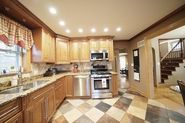 kitchen with visible vents, decorative backsplash, arched walkways, appliances with stainless steel finishes, and a sink