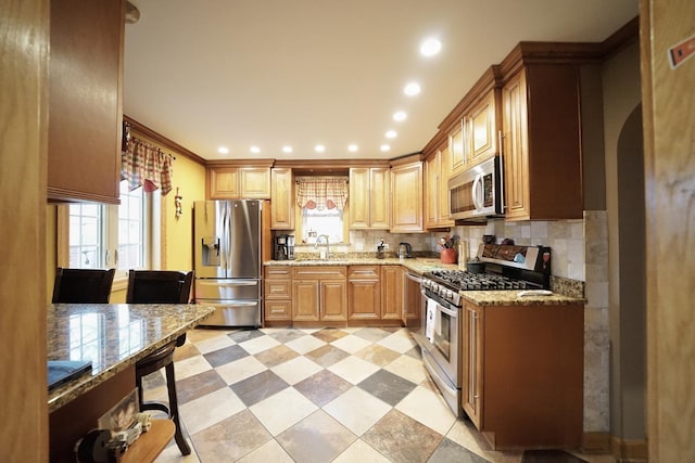 kitchen with recessed lighting, a sink, appliances with stainless steel finishes, light stone countertops, and tasteful backsplash