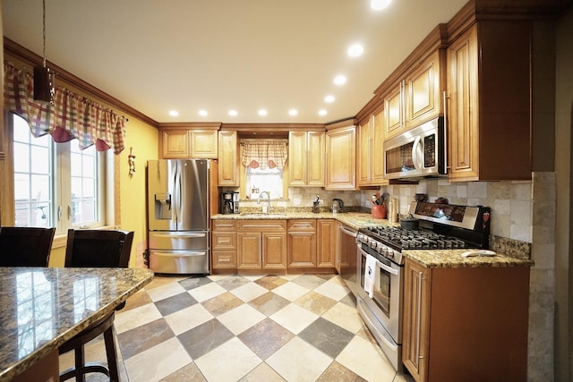 kitchen featuring appliances with stainless steel finishes, a sink, light stone countertops, light floors, and backsplash