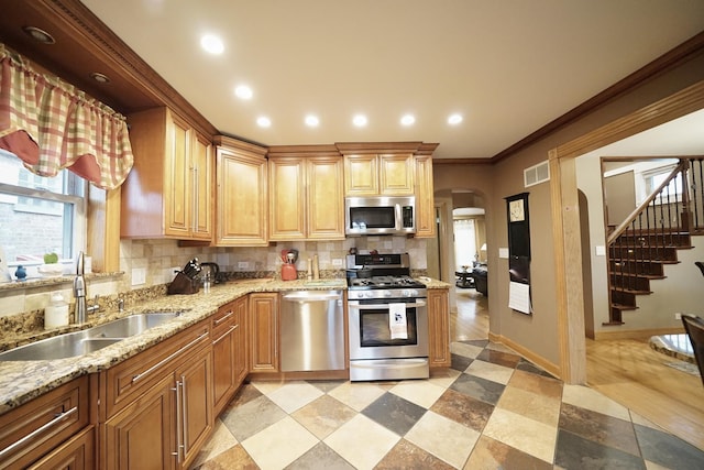 kitchen featuring arched walkways, stainless steel appliances, recessed lighting, decorative backsplash, and a sink