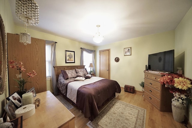 bedroom featuring light wood-style floors, baseboards, and a chandelier