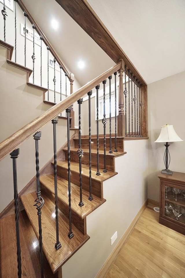 staircase featuring baseboards and wood finished floors