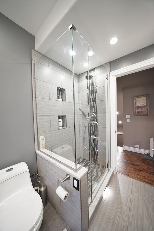 full bath featuring toilet, a shower stall, baseboards, and wood finished floors