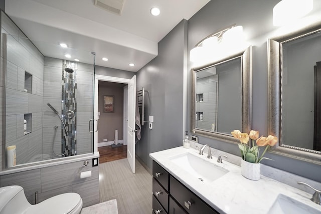 full bath with visible vents, tiled shower, a sink, and toilet