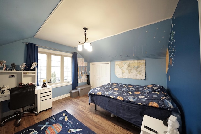 bedroom with lofted ceiling, a closet, wood finished floors, and baseboards