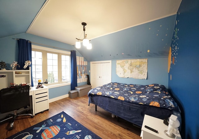 bedroom with lofted ceiling, a closet, baseboards, and wood finished floors