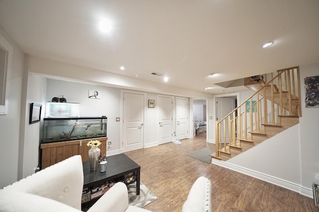 living area with recessed lighting, visible vents, wood finished floors, baseboards, and stairs