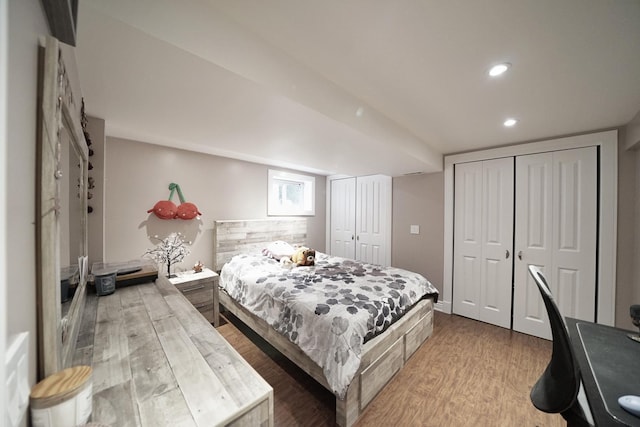 bedroom with recessed lighting, wood finished floors, and two closets