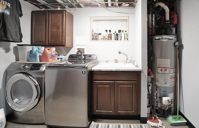 laundry room with a sink, gas water heater, washing machine and clothes dryer, and cabinet space