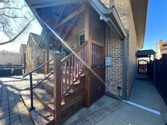 view of side of home featuring fence and brick siding