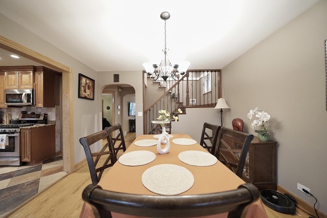 dining area featuring arched walkways, baseboards, stairs, and a notable chandelier