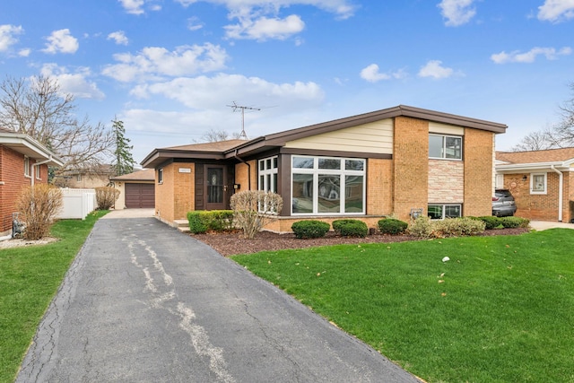 view of front facade featuring brick siding, a front yard, fence, and a detached garage