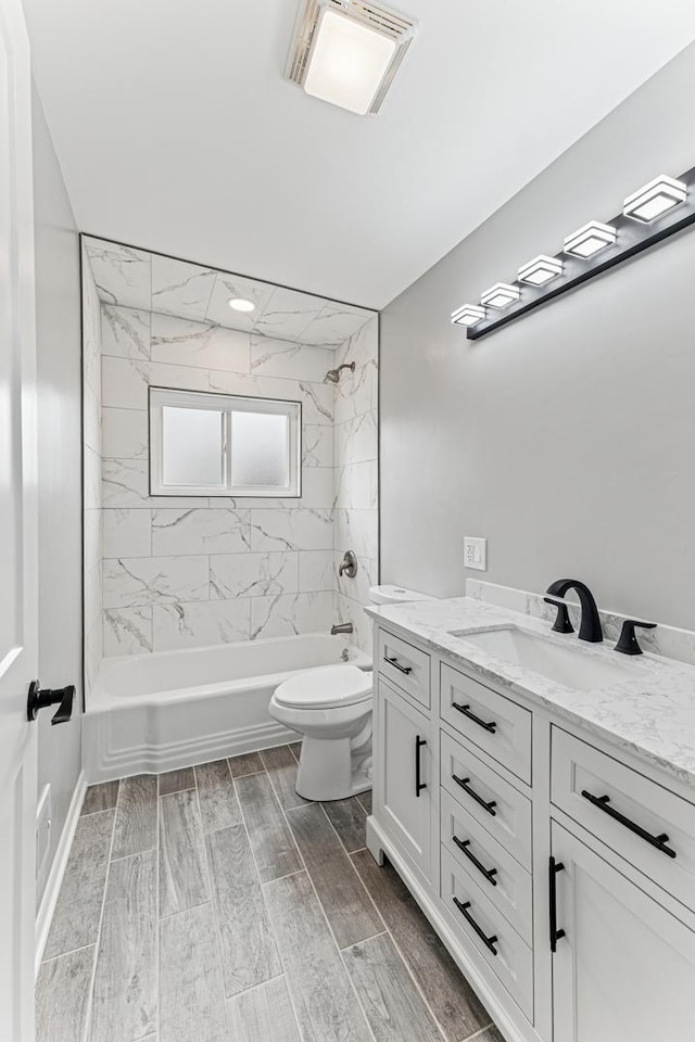 bathroom with visible vents, toilet, vanity, wood finished floors, and shower / bath combination