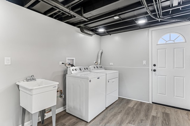 clothes washing area with laundry area, wood finished floors, a sink, and washer and clothes dryer