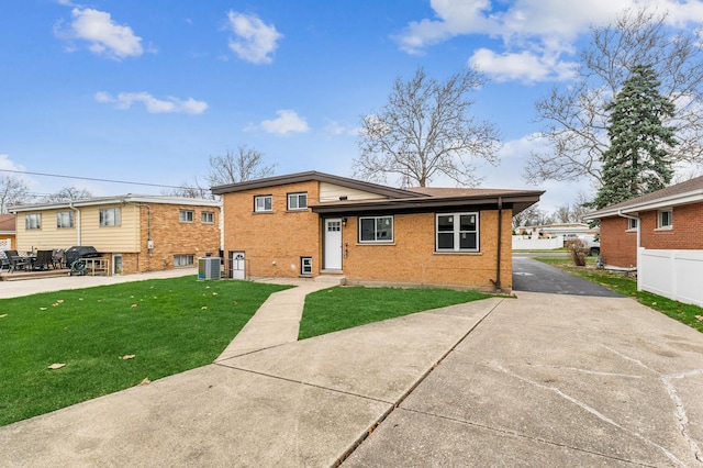 back of house featuring a patio, central air condition unit, brick siding, fence, and a lawn