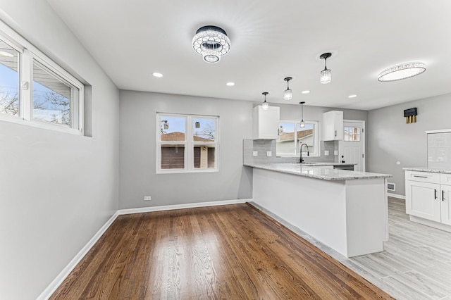 kitchen with white cabinets, light wood finished floors, baseboards, and light stone countertops