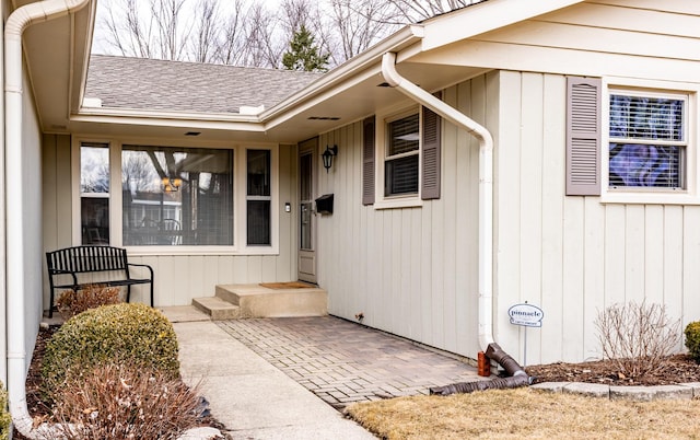 entrance to property featuring roof with shingles