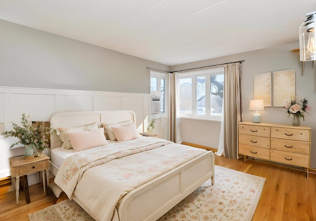 bedroom featuring light wood-type flooring and wainscoting