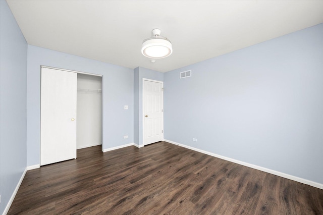 unfurnished bedroom featuring dark wood-style floors, a closet, visible vents, and baseboards