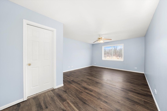 empty room featuring a ceiling fan, baseboards, and dark wood-style flooring