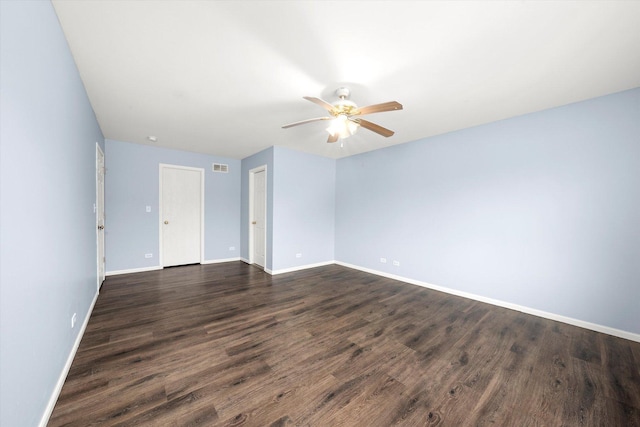 spare room with a ceiling fan, visible vents, baseboards, and dark wood-type flooring