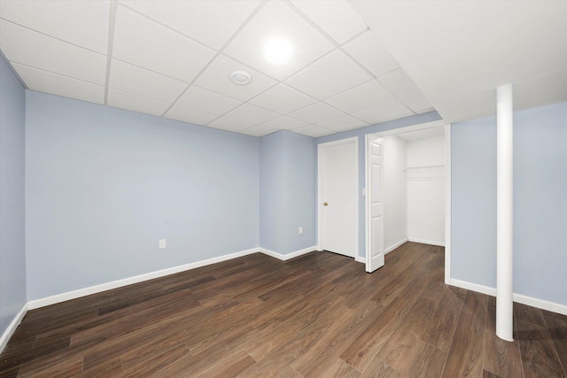 finished below grade area with baseboards, a drop ceiling, and dark wood-style flooring