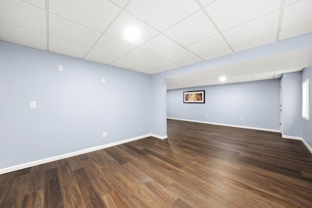 interior space with baseboards, a drop ceiling, and wood finished floors