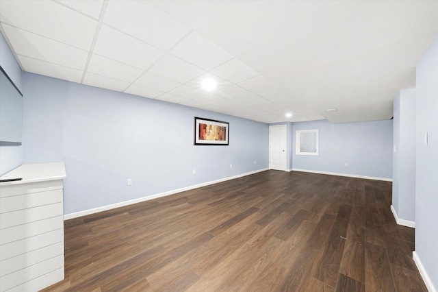 interior space with baseboards, a drop ceiling, and wood finished floors