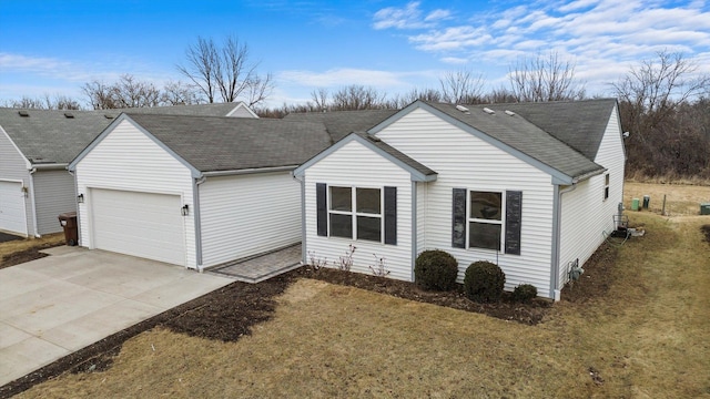 single story home featuring driveway, roof with shingles, and an attached garage