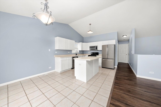 kitchen featuring a kitchen island, stainless steel appliances, light countertops, white cabinetry, and a sink