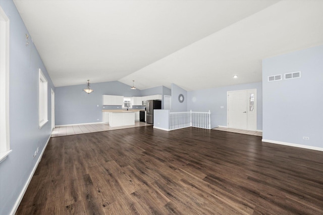 unfurnished living room featuring lofted ceiling, visible vents, and wood finished floors