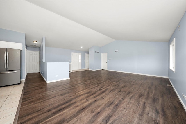 unfurnished living room featuring visible vents, vaulted ceiling, baseboards, and wood finished floors