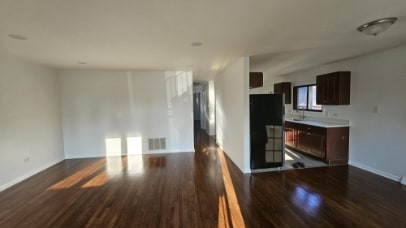 unfurnished living room with baseboards, visible vents, and dark wood finished floors