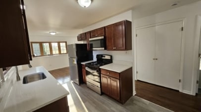 kitchen featuring dark wood-type flooring, stainless steel microwave, gas stove, and freestanding refrigerator