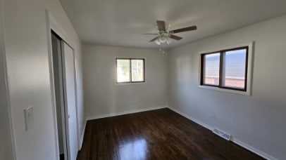 unfurnished bedroom with a ceiling fan, visible vents, baseboards, a closet, and dark wood finished floors